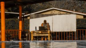 a man standing in front of a table with a laptop at Joe's Layover Hostel Boquete in Boquete