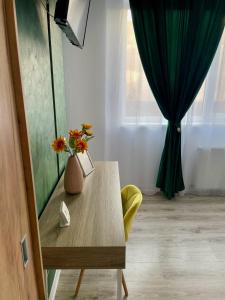 een kamer met een tafel met een vaas met bloemen erop bij Greenlight Studio by DAT Apartments in Cluj-Napoca