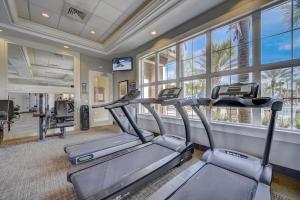a gym with two cardio machines in a room with windows at Marvelous Villa, South facing pool and hot tub, themed bedrooms near Disney in Davenport