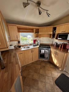 a small kitchen with wooden cabinets and a stove at Bay 1 in Kirkcolm
