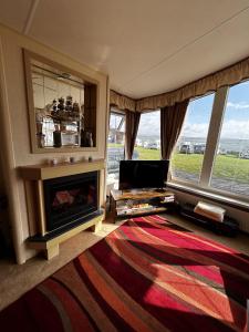 a living room with a fireplace and a large window at Bay 1 in Kirkcolm