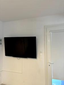 a flat screen tv hanging on a white wall at Minimal Grey Apartment Pool-front in Paros in Parikia