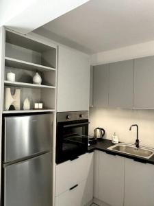 a kitchen with white cabinets and a stainless steel refrigerator at Minimal Grey Apartment Pool-front in Paros in Parikia