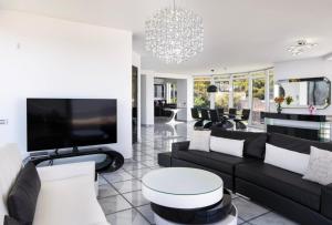 ein Wohnzimmer mit schwarzen und weißen Möbeln und einem TV in der Unterkunft Villa Coral Luxury Resort in Agios Spyridon