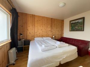 1 dormitorio con 1 cama y 1 sofá rojo en Fagrabrekka Private Room, en Staður