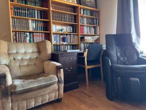 uma sala de estar com um sofá e uma estante de livros com livros em Fagrabrekka Private Room em Stadur