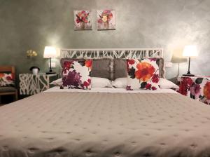 um quarto com uma cama grande e almofadas florais em Affittacamere Casa Mac & Rose em San Quirico dʼOrcia