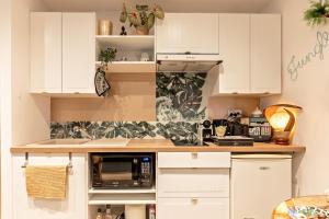a kitchen with white cabinets and a microwave at Jungle Spa - Cocon romantique et tropical avec jacuzzi privé ! in Pézenas