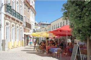 a group of people sitting at tables under umbrellas on a street at Boutique Rooftop with Ocean views in São Martinho do Porto