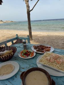 stół z talerzami jedzenia na plaży w obiekcie Marvel loli camp w mieście Al-Kusajr