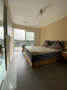 ein Schlafzimmer mit einem Bett und einem großen Fenster in der Unterkunft Penthouse Apartment mit Alpenblick in Friedrichshafen