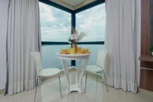 uma mesa branca e cadeiras num quarto com uma janela em Tropical Executive N 905 em Manaus