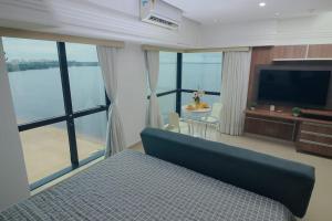 um quarto com uma cama e uma televisão e algumas janelas em Tropical Executive N 905 em Manaus