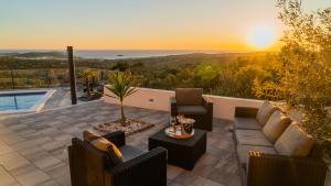 un patio avec un canapé et des chaises et le coucher du soleil dans l'établissement Villa Alacinda, à Rogoznica