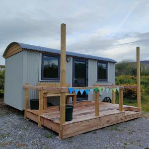 a tiny house on a deck with a porch at DANÚ Shepherd's Hut in Tralee