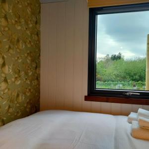 a bedroom with a bed and a window with towels at DANÚ Shepherd's Hut in Tralee
