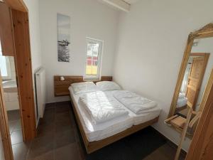 ein kleines Schlafzimmer mit einem Bett und einem Spiegel in der Unterkunft Küstenferienhaus in Stahlbrode