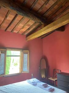 - une chambre avec des murs rouges, un lit et une fenêtre dans l'établissement Al Sangallo Agriturismo, à Montecarlo