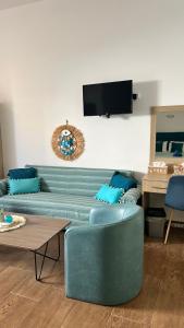 a living room with a blue couch and a table at Grande Blue Suites with private bay in Archangelos