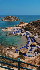 a beach with umbrellas and people in the water at Grande Blue Suites with private bay in Archangelos