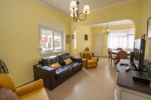 ein Wohnzimmer mit Ledercouch und Fernseher in der Unterkunft Casa Branca in Armação de Pêra