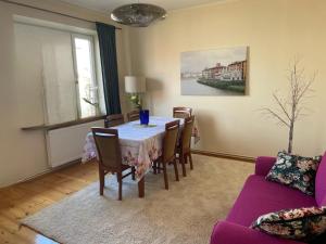 Apartament na Skorupki في أوغستوف: غرفة طعام مع طاولة وكراسي وأريكة أرجوانية