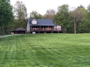 una casa su una collina con un grande prato di Dancing Barefoot Farms a Pawlet
