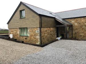 a large brick building with a large garage at Apple Tree Barn - converted barn with meadow views in Helston