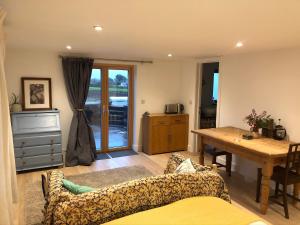 a living room with a couch and a table at Apple Tree Barn - converted barn with meadow views in Helston