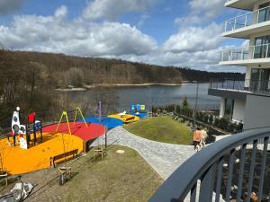 a balcony of a building with a playground next to a lake at Apartament Przystań 2 in Kartuzy