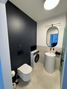 a bathroom with a toilet sink and a washing machine at Apartament Przystań 2 in Kartuzy