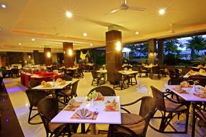 a restaurant with white tables and chairs and tablesearcher at Pangeran Beach Hotel in Padang