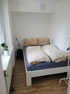 Cama en habitación con pared blanca en Nový apartman Eva, en Jičín