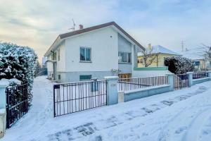 een wit huis met een hek in de sneeuw bij Maison individuelle 100 m2, jardin et parking privé in Colmar