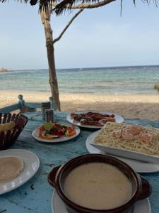 a table with plates of food on the beach at Marvel loli camp in Quseir