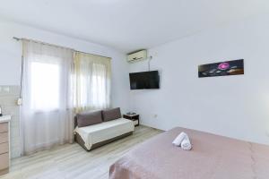 - une chambre blanche avec un lit et une chaise dans l'établissement Apartmani Stadion, à Zadar
