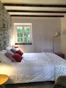 a bedroom with a large white bed with red pillows at La maison du four à pain in Grandchamp