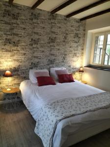 1 dormitorio con 1 cama grande y pared de ladrillo en La maison du four à pain en Grandchamp