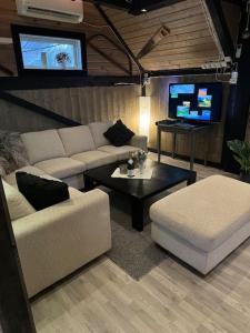 uma sala de estar com um sofá, uma mesa e uma televisão em Koselig låve em Ålesund