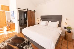 1 dormitorio con 1 cama grande con sábanas blancas en Tempel Wines, en Paarl