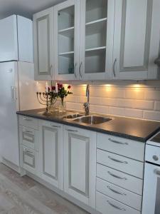 a kitchen with white cabinets and a sink and a refrigerator at A new apartment close to City in Boden
