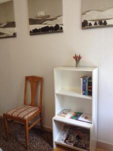 a chair sitting next to a book shelf with books at Marielund Gård in Skara
