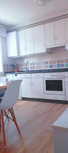 a kitchen with white cabinets and a table and a microwave at Apartamento Sobreira en centro Allariz con WIFI in Allariz