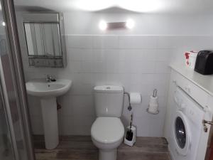 a white bathroom with a toilet and a sink at Apartamentos Santillán in San Vicente de la Barquera +69 photos
