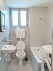 a white bathroom with a toilet and a sink at Fellini Marcello garden (talpiot) in Haifa