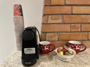 einen Mixer neben zwei Tassen Kaffee in der Unterkunft Suites Kozi in Sarandë