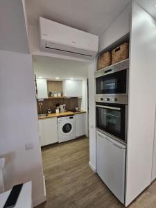 a small kitchen with white appliances and a counter at Casa da Aldeia in Olhos de Água