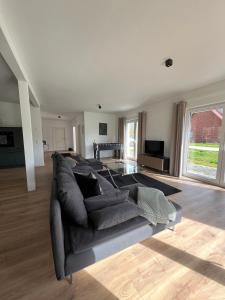 ein Wohnzimmer mit einem grauen Sofa und einem Tisch in der Unterkunft HOME OF VACATION - Ferienhaus bei Celle nähe Hannover - FREE WIFI & Netflix in Adelheidsdorf