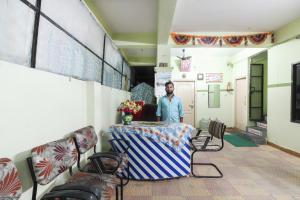 a man standing next to a table in a room at SPOT ON 9 Star Guest House in Kondapur