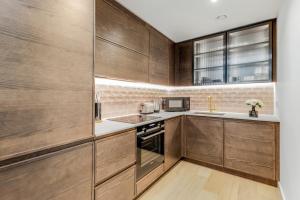 a kitchen with wooden cabinets and a microwave at Khayat Homes - The Lord - One Bed Luxury Apt in London